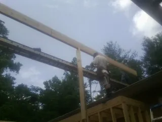Carpenter setting a ridge beam over a new addition frame — Ice Dam Removal by Roofing Brothers in Amite