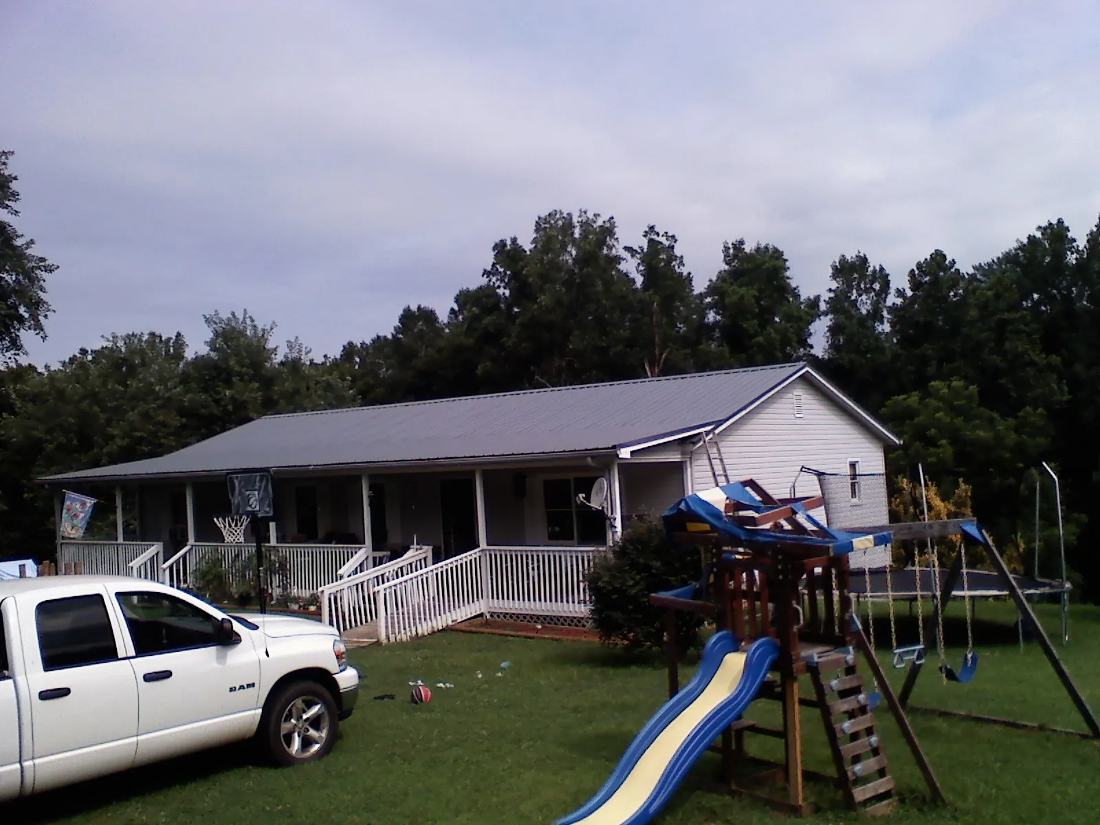 Dark metal roof on a country home with a full length front porch in Amite