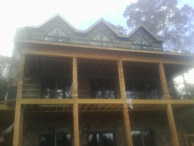 Dormers and porch framing on a large log home under construction — Roof Coating work by our crew in Amite