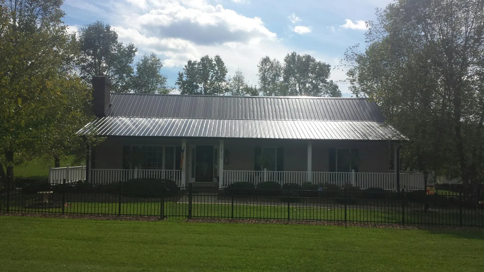 Gray metal roof on a brick ranch with a full width front porch — Gutter Guard Installation work by our crew in Amite