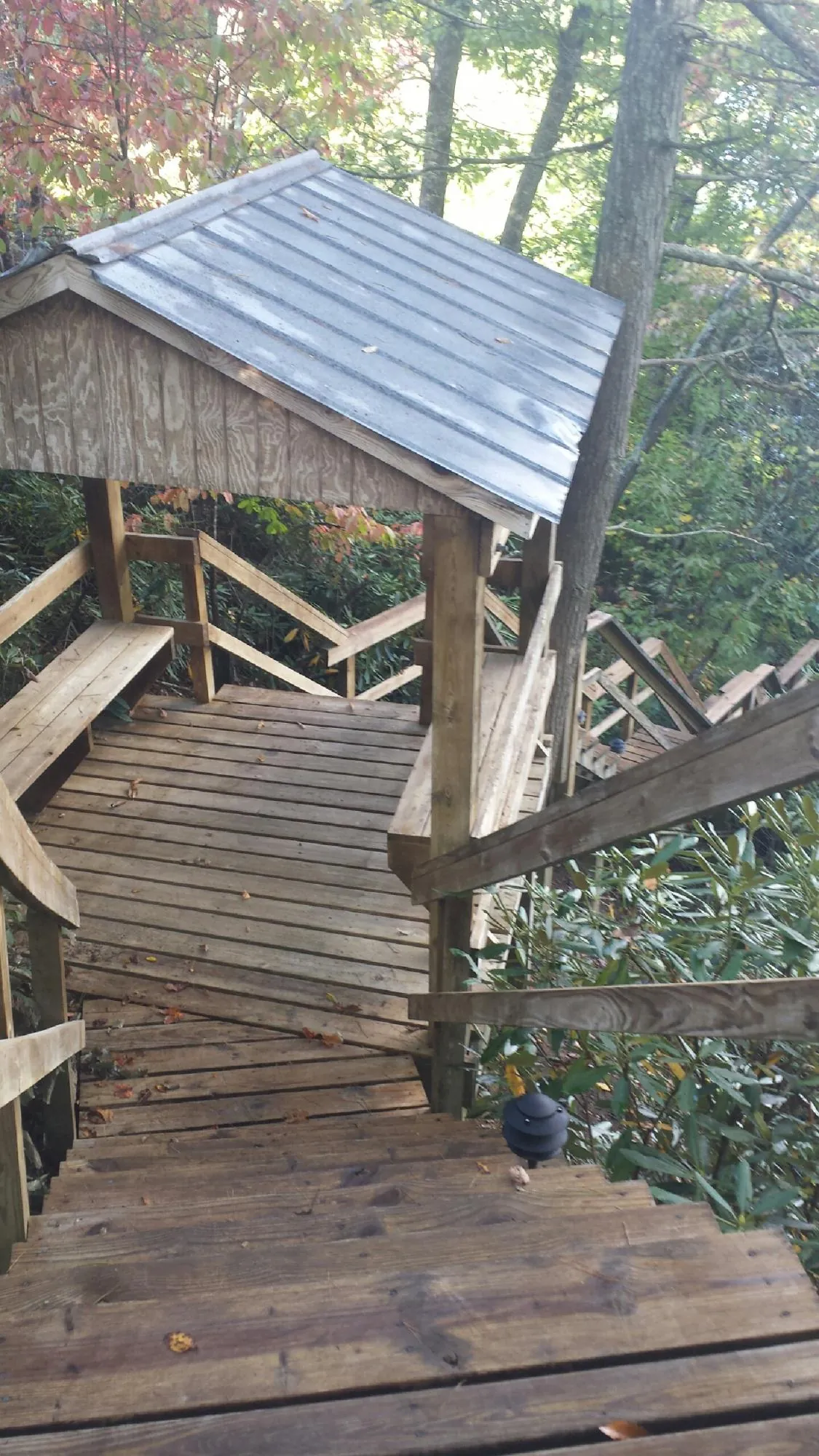 Metal roofed shelter over wooden steps on a wooded walkway — Skylight Repair & Installation work by our crew in Amite